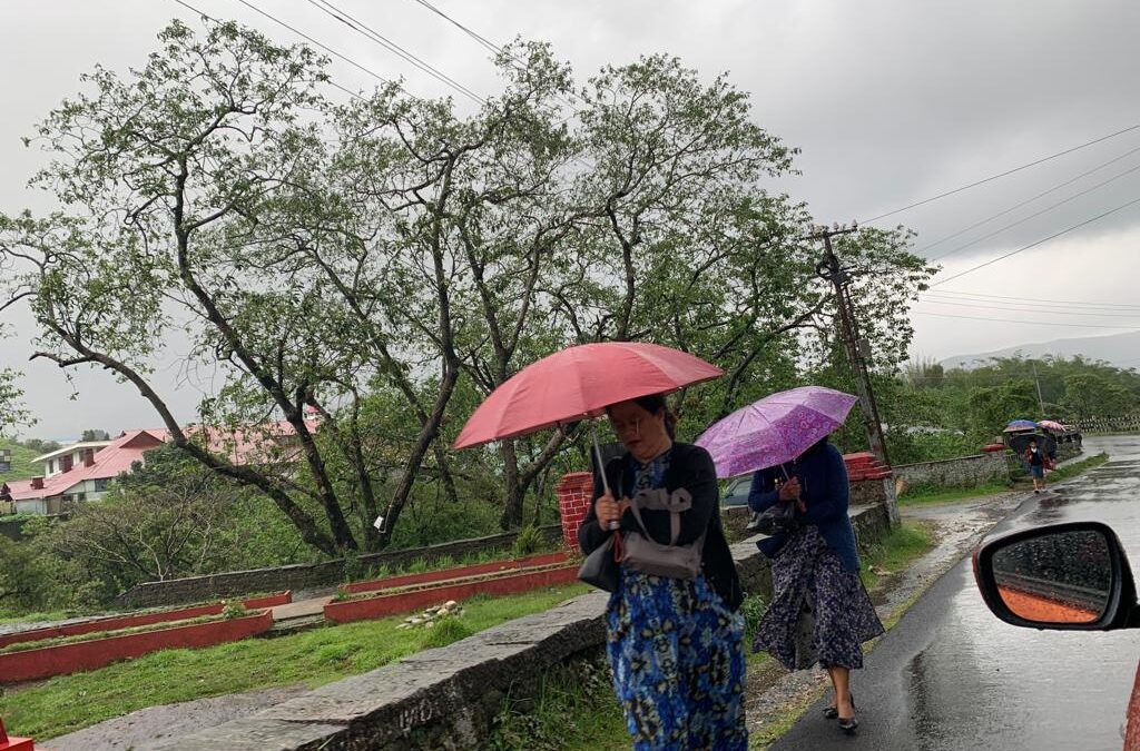 Indian women walking in the monsoon rains holding umbrellas